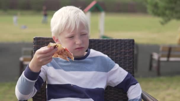 Junge Blondine isst Pizza in einem Straßenrestaurant. — Stockvideo