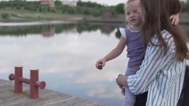 En kvinna bär en liten flicka i famnen. — Stockvideo