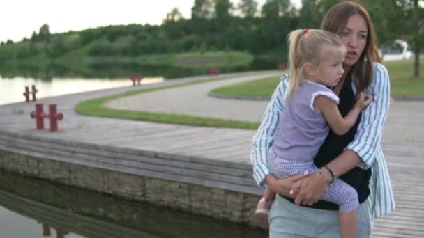 Una mujer lleva a una niña en sus brazos — Vídeos de Stock
