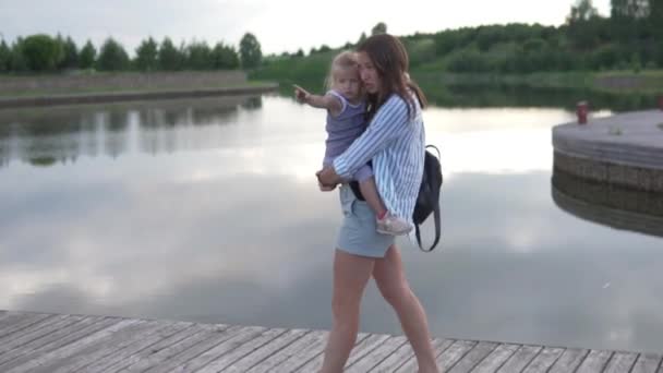 Bir kadın küçük bir kızı kollarında taşır.. — Stok video