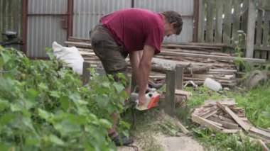 Yazlıkta elektrikli testereyle odun kesen bir adam.