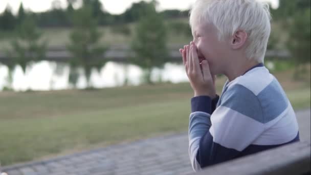 Ein blonder Junge, der bei einem Spaziergang fröhlich lacht — Stockvideo