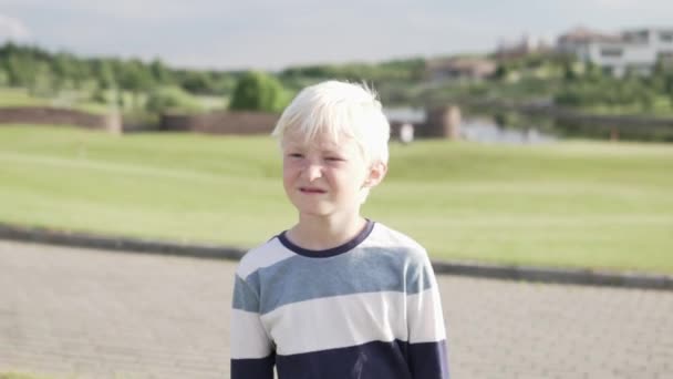 Bonito menino loiro caminha no parque no verão — Vídeo de Stock