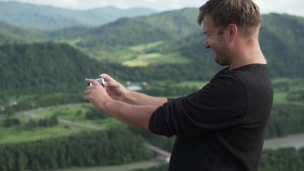 Een man maakt op de telefoon een foto van de aard van de zomer Altai — Stockvideo