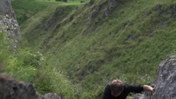 Un uomo difficilmente si arrampica sulla collina — Video Stock