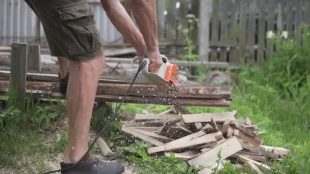 Un hombre está aserrando madera con una sierra eléctrica — Vídeo de stock