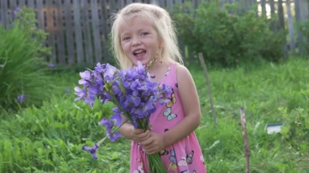 La niña se ríe con un ramo de flores en las manos . — Vídeos de Stock