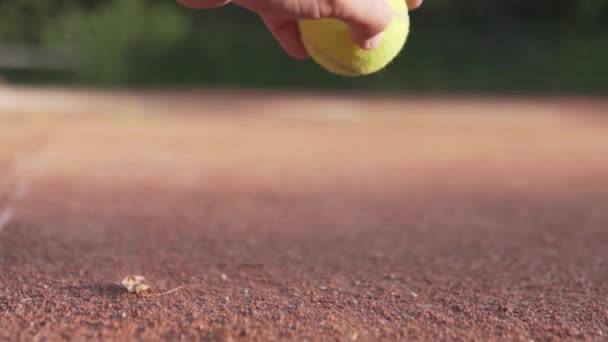Egy férfi kéz felveszi a teniszlabdát a salakos bíróság — Stock videók