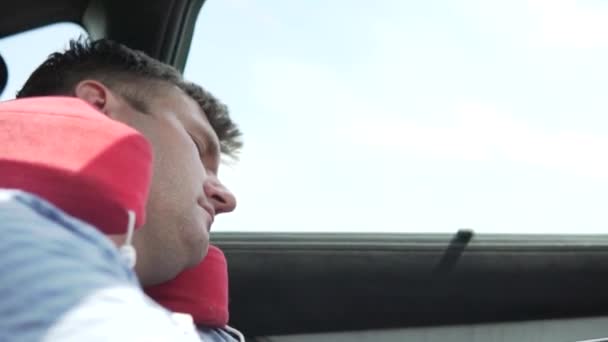 Ένας όμορφος άντρας κοιμάται σε ένα αυτοκίνητο σε ένα μαξιλάρι που ταξιδεύει — Αρχείο Βίντεο
