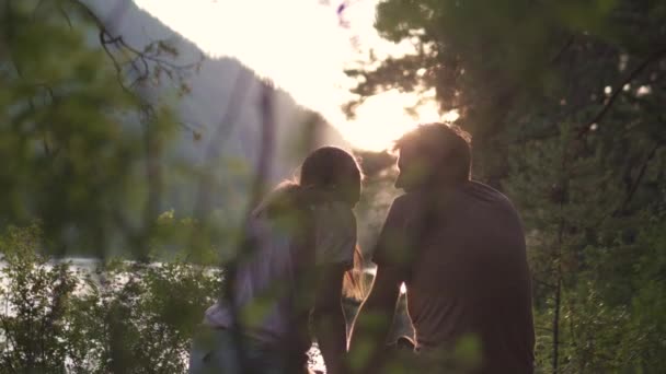 Dvojice zamilovaná sleduje západ slunce u horské řeky — Stock video