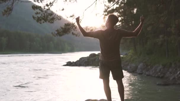 Veselý mužský stopař oslavuje, jak se blíží k vrcholu idylický východ slunce. — Stock video
