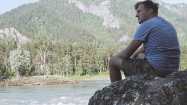 Ένας άνθρωπος κοιτάζει σε ένα ορεινό ποτάμι στο Altai. — Αρχείο Βίντεο
