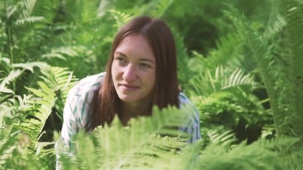 Een vrouw zit in de Fern struikgewas en lacht — Stockvideo