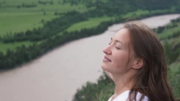 Όμορφη νεαρή γυναίκα κοιτάζει το ποτάμι από την κορυφή του βουνού — Αρχείο Βίντεο