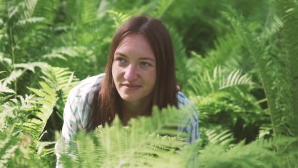 A woman sits in the fern thickets and laughs. — Stock Video