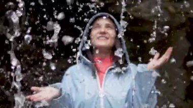 genç kadın bir şelalenin su altında duruyor.