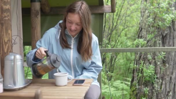 Una mujer bebe té por la mañana en el bosque cerca de la tienda — Vídeos de Stock