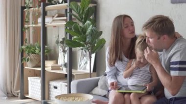 Ebeveynler ve küçük kızı tablet üzerinde gelişmekte olan bir oyun oynamak