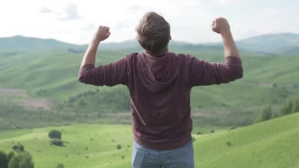 Masculino trekker levanta braços gozando montanha vista superior no verão — Vídeo de Stock