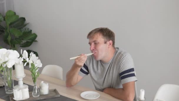 Un homme mange des sushis prêts à la maison à la table . — Video