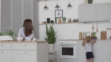 Sabah evde bir çocukla. Annem mutfakta oturur ve kahve içer.,