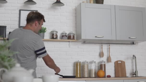 Hombre preparando el desayuno en la cocina y bailando divertido — Vídeo de stock