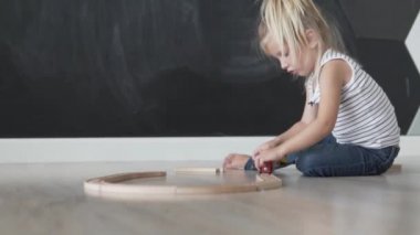 Güzel küçük kız oyun odasında tren için ahşap bir yol inşa
