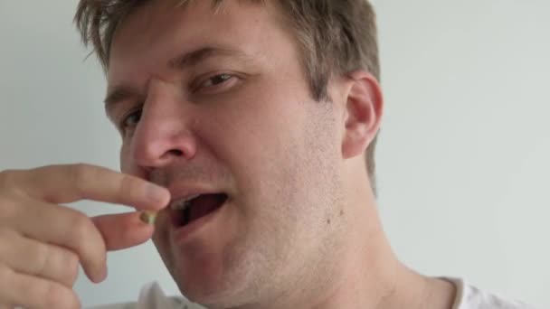 Ένας άντρας καταπίνει ένα λευκό χάπι και το πίνει με νερό — Αρχείο Βίντεο