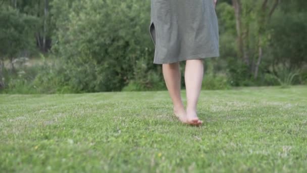 Jambes femelles marchant lentement à travers l'herbe verte — Video