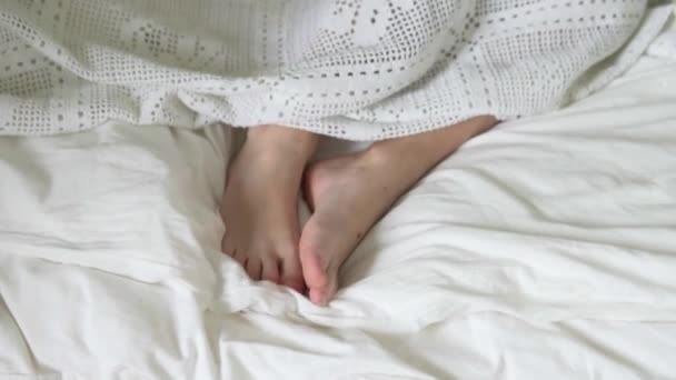 Crianças é pés se movem sob um cobertor branco — Vídeo de Stock