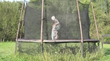 Çocuklar yaz aylarında dışarıda bir trambolin üzerinde atlama