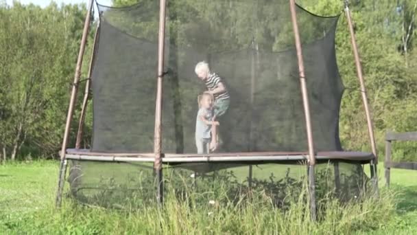 Kinderen springen op een trampoline buiten in de zomer — Stockvideo