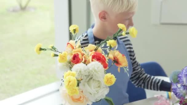 A boy collects a bouquet of artificial flowers in the childrens city — Stock Video