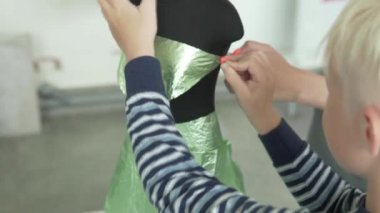 Çocuk bir mannequi bir elbise yapar