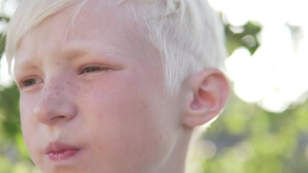 Lindo menino loiro comendo uma maçã no jardim — Vídeo de Stock