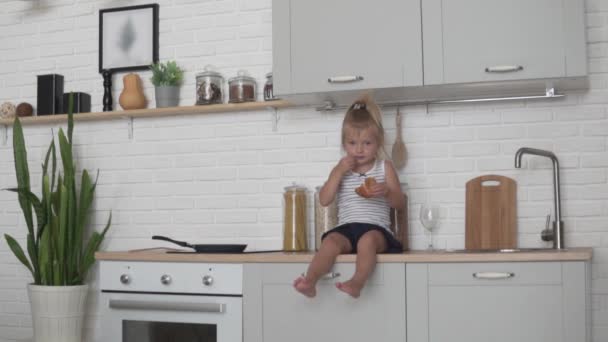 Little girl eating bread in the kitchen — Stock Video