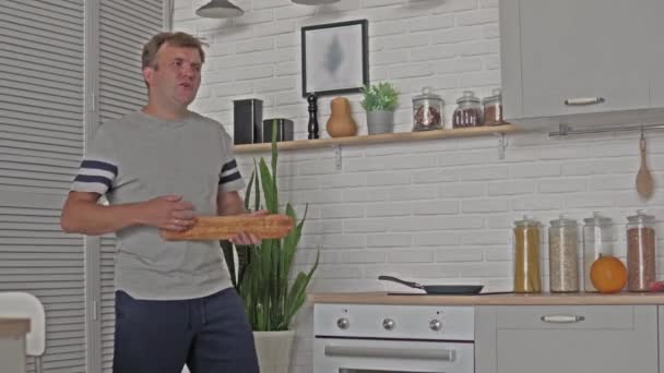 Un hombre divirtiéndose con una barra de pan blanco — Vídeos de Stock