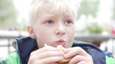 Aç albino çocuk sokakta hamburger yiyor