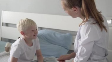 Hastanede tedavi üzerinde oturan bir doktor ve bir çocuğun neşeli selamlama