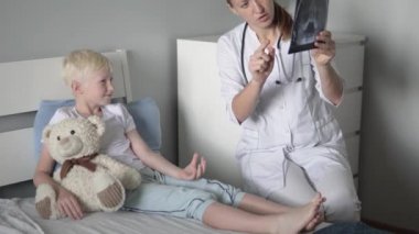 Doktor çocuğa sinüslerin röntgenini gösterir.