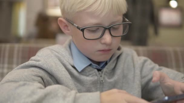 Um rapaz com óculos joga xadrez num telemóvel — Vídeo de Stock