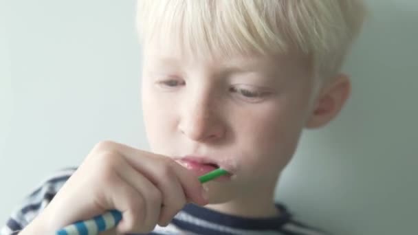 Niño rubio cepilla los dientes con pasta de dientes — Vídeo de stock