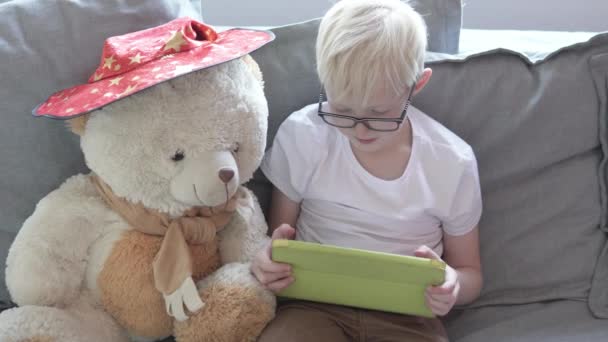 Bonito menino loiro joga jogos no tablet . — Vídeo de Stock