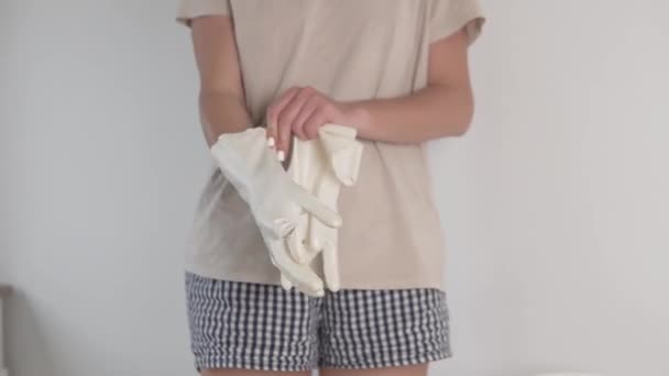 De vrouw trekt beschermende handhandschoenen aan voordat ze het appartement schoonmaakt. — Stockvideo
