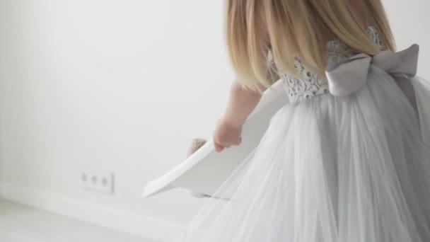 Маленькая девочка в умном платье играет с плюшевым мишкой — стоковое видео
