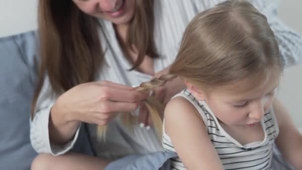 Mãe tranças de manhã para uma pequena filha de crianças — Vídeo de Stock