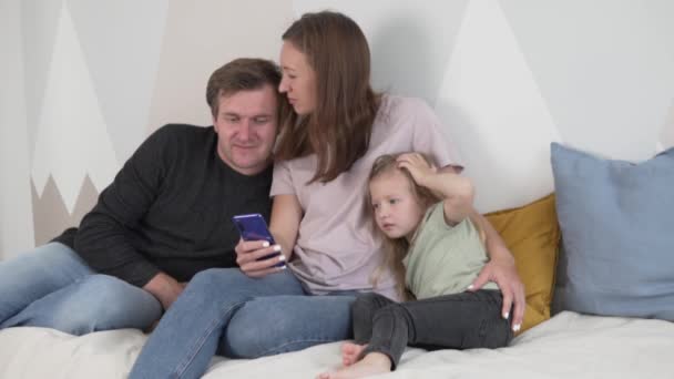 幸せな家族のお父さん、お母さん、娘さんが携帯電話で写真を見る — ストック動画
