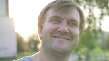 Yazın parkta yürürken gün batımında mutlu bir adamın yakın çekimi..