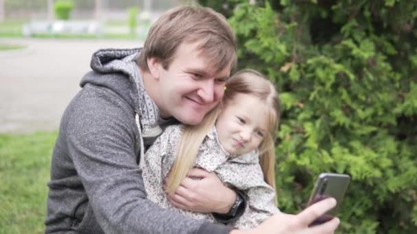 Papá toma una foto selfie en un teléfono móvil con una hermosa hijita — Vídeo de stock