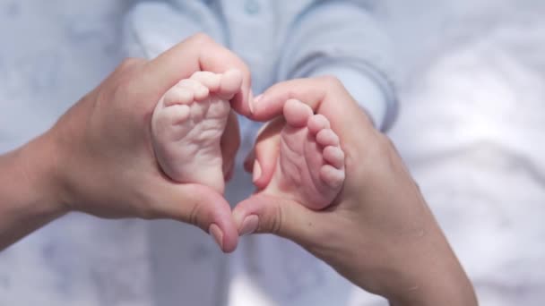 Las manos de las mujeres hacen que el corazón de las piernas del bebé — Vídeo de stock